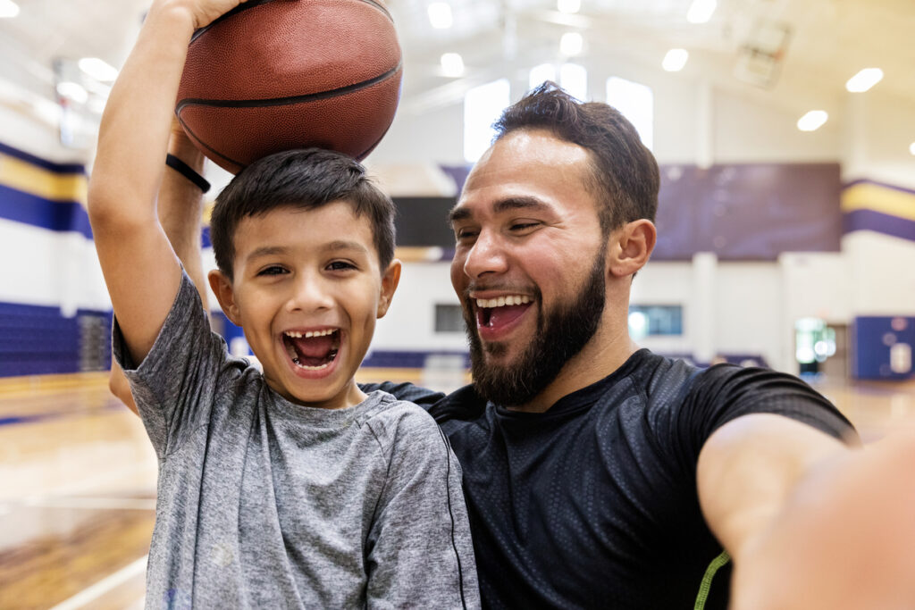 child and adult caregiver playing basketball