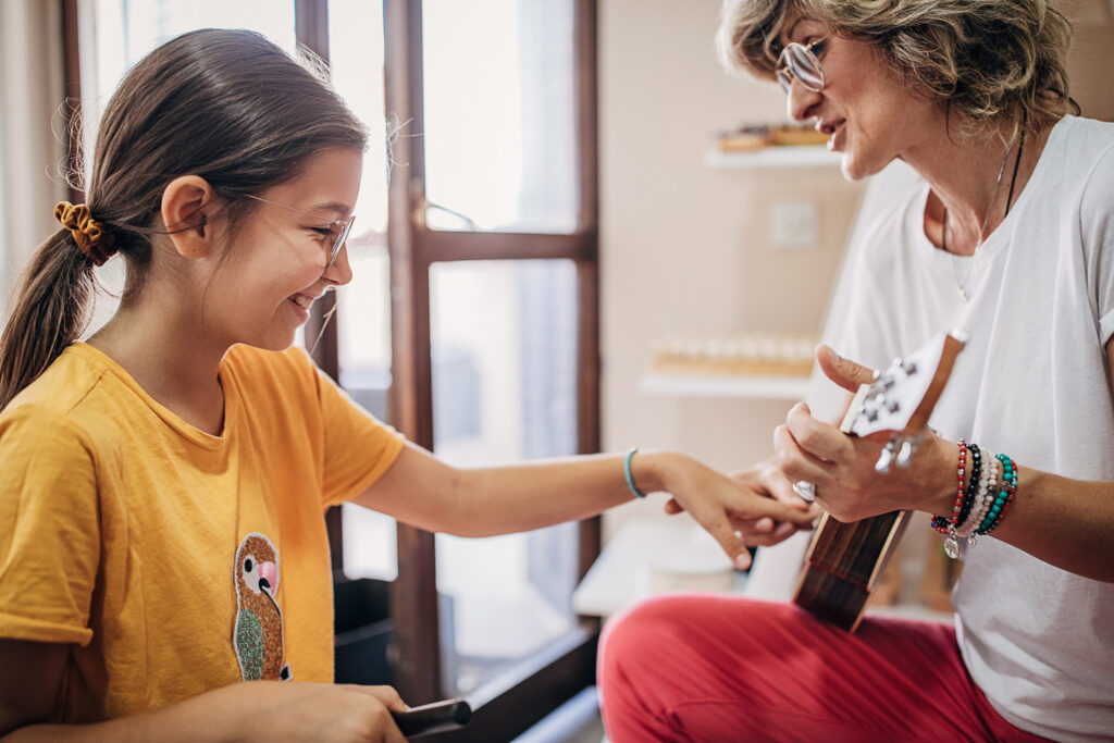 Girl learning about a stringed instrument from a woman - music therapy example