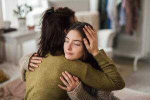 Teenage daughter and mother hugging
