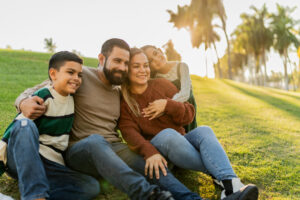 Family sitting on ground in public park.