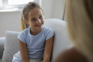 Young girl sitting on the couch and looking at an adult.