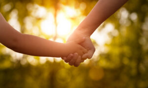Close up of siblings holding hands at the sunset.