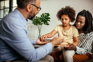 A caregiver and child meet with a mental health professional to discuss goals, challenges and available support.