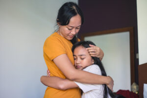Mother comforts her daughter, offering emotional support and empathy in a time of need. 